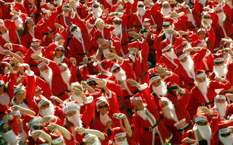 Image: People dressed in Santa costumes warm up before the start of a 5km charity race in central Sydney