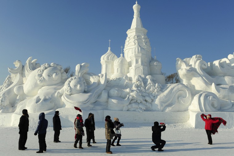 Image: Tourists take pictures in front of a snow sculpture ahead of the 13th Harbin Ice and Snow World in Harbin