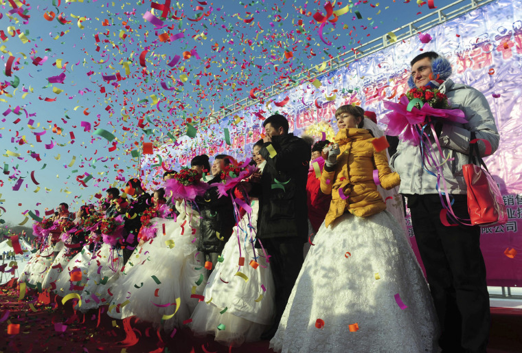 Image: Confetti is thrown at couples during a group wedding ceremony in Harbin