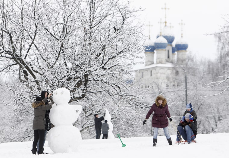 Image: People build snowmen and ride a snow sledge in Moscow