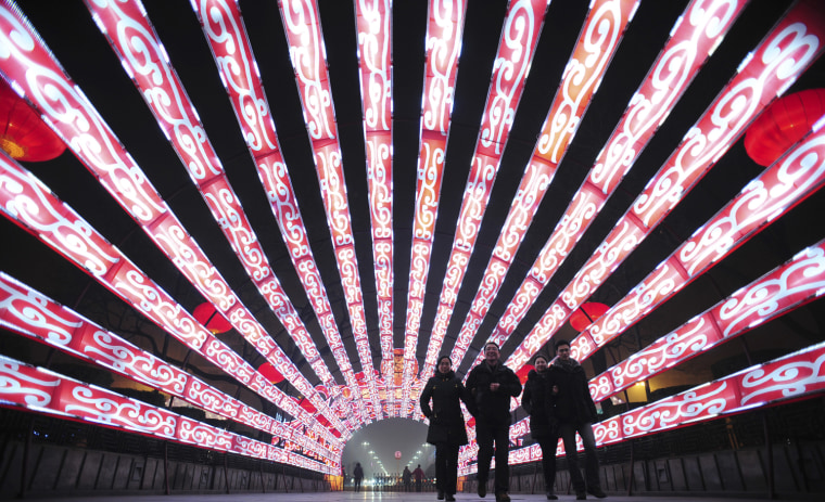 Image: Visitors walk through a tunnel made up of lanterns which have been set up for the upcoming Spring Festival in Xi'an