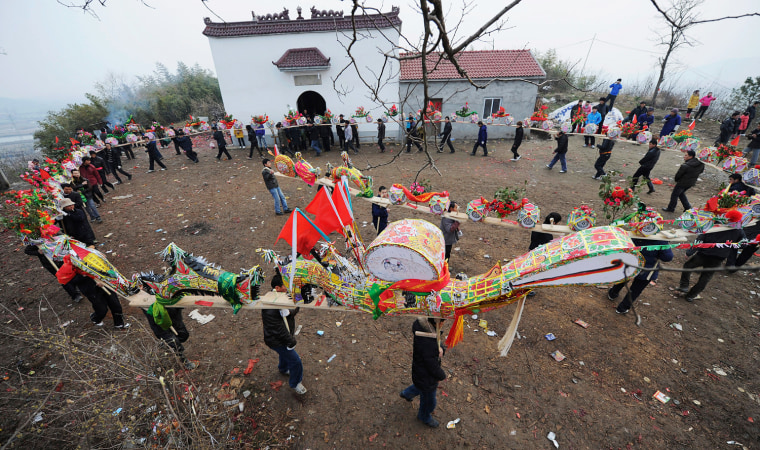 Image: Residents carry a 'dragon', constructed using wooden benches and decorations, as they perform a dragon dance on the second day of the Chinese Lunar New Year at a village in Wuhu,Anhui province