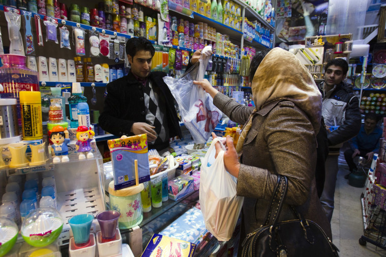 Image: A woman makes a purchase at a store in Tehran
