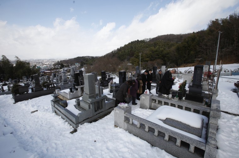 Image: Koyu Abe, a Zen priest, prays before a grave along with bereaved family members at the Joenji temple in Fukushima