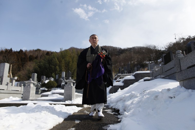 Image: Koyu Abe, a Zen priest, walks through a graveyard in the snow at the Joenji temple in Fukushima