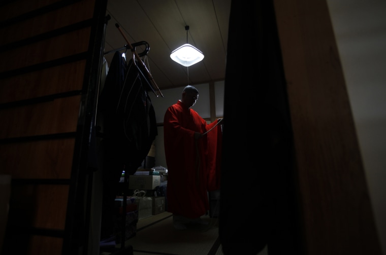 Image: Koyu Abe, a Zen priest, changes his clothes before a traditional Buddhist memorial service at his Joenji temple in Fukushima, northern Japan