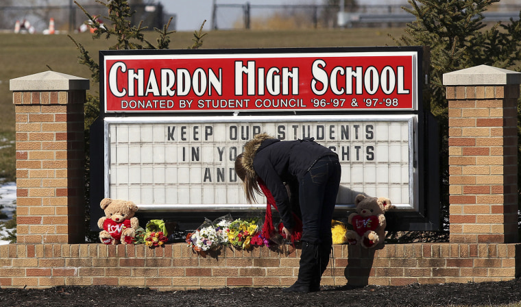Image: An unidentified female student places a bouquet of roses at the base of the Chardon High School sign in Chardon