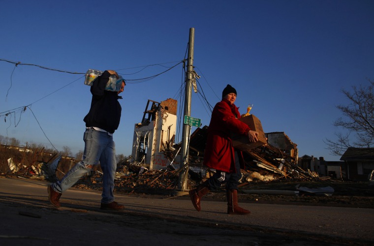 Image: People carry supplies past a church damaged by a chain of tornadoes is seen in West Liberty