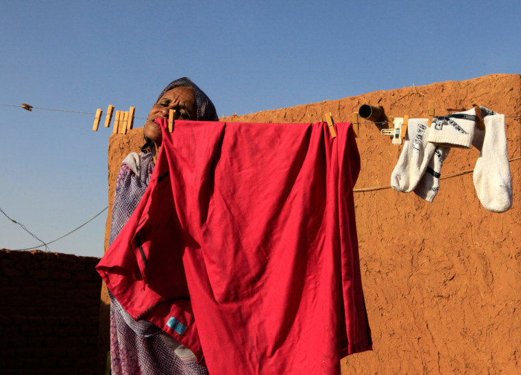 Image: Hokom Al, a disabled woman, uses her mouth to hang clothes to dry in a rural area in Khartoum