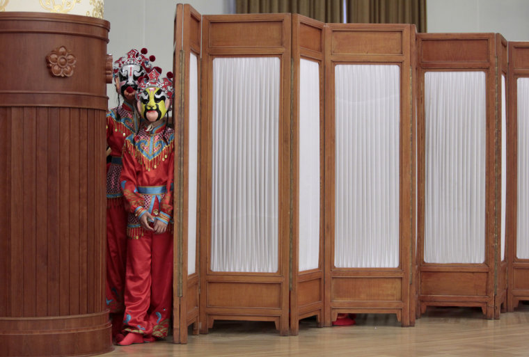 Image: Girls wearing Peking opera masks wait to at the Great Hall of the People in Beijing