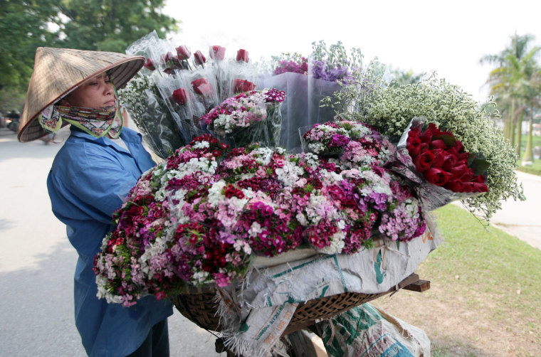 Image: A woman sells flowers on a street in Hanoi