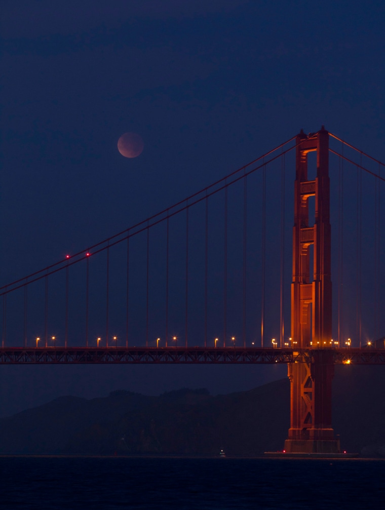 Image: A lunar eclipse is seen over the south tower of the Golden Gate Bridge in San Francisco