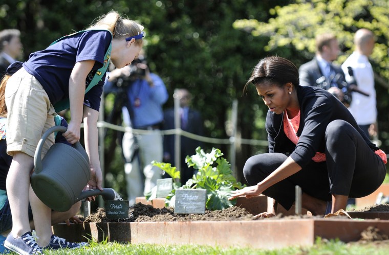 Image: U.S. first lady Michelle Obama works with school children for the fourth annual White House Kitchen Garden spring planting on the South Lawn of the White House in Washington