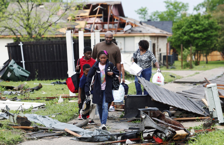 Image: A family walks through the debris after their neighborhood was damaged by a series of tornadoes ripped through the Dallas suburb of Lancaster