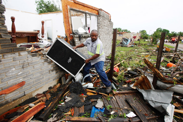 Image: Jason Moffett carries moves belongings out of a house which was destroyed after a series of tornadoes ripped through the Dallas suburb of Lancaster