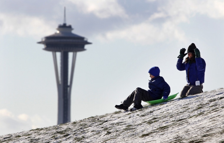 Image: A sledder starts downhill after a push as the Space Needle is seen behind Tuesday, Nov. 23, in Seattle's Gasworks Park