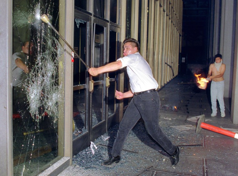 A rioter breaks a glass door of the Criminal Court