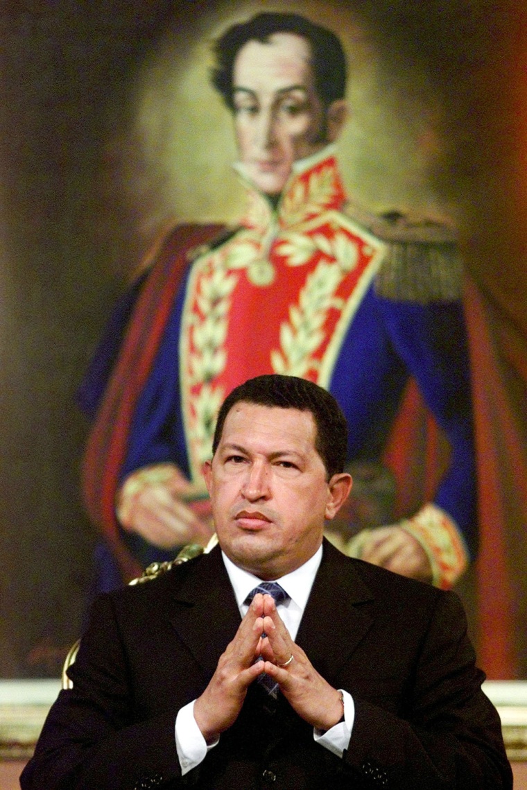 Image: Venezuelan President Hugo Chavez sits in front of a painting of the country's liberation hero Simon ..