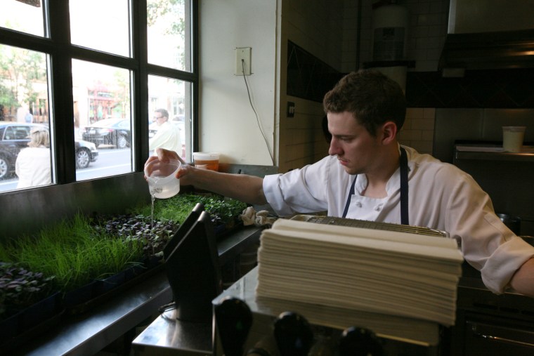 An employee at Clio restaurant in Boston waters the window herb garden