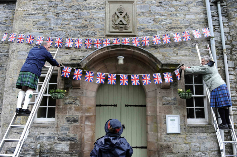 Image: Richard McCutcheon (L), Liz Rattray (C) and Donald Isles hang Union Flags above the entrance to the village hall in Blair Atholl