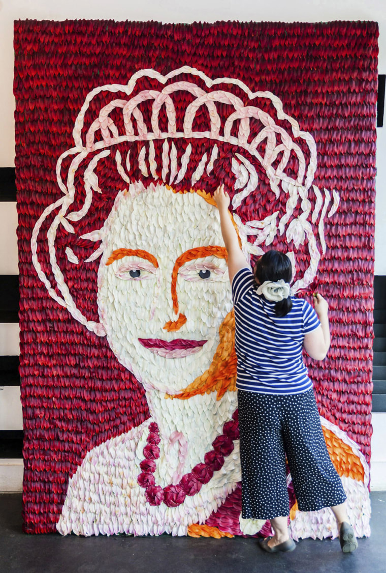 Image: A florist puts the finishing touches on a 3 metre x 2 metre portrait of the Queen made out of over 6,000 lily petals in London