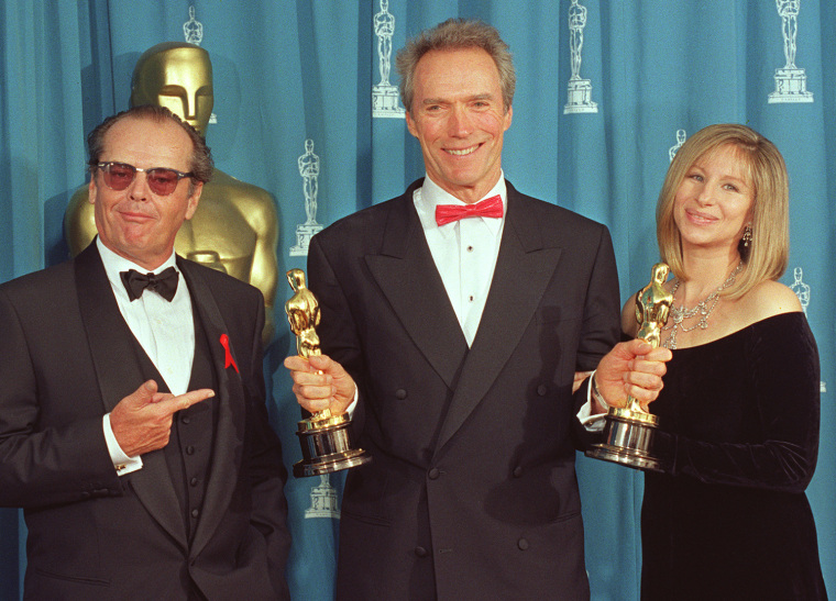 Image: US actor Clint Eastwood (C) holds up his two Oscar