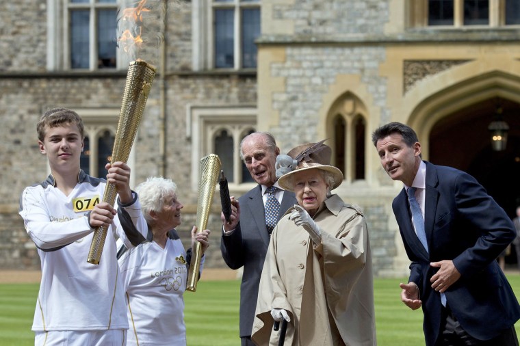 Image: Queen Elizabeth, Prince Philip, LOCOG Chairman Coe and torch bearer Macgregor watch as torchbearer Wells takes the Olympic Flame at Windsor Castle, west of London