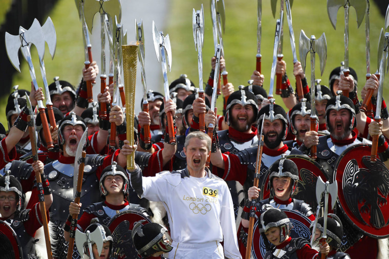 Image: Torch bearer Mathew Cox shouts as he holds aloft the London 2012 Olympic torch while surrounded by the Jarl vikings in Lerwick in the Shetland Islands