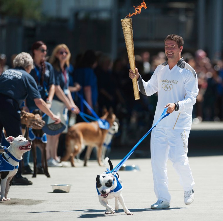 Image: Former England striker Michael Owen carries the Olympic Torch through Battersea dogs home with a Staffordshire Bull Terrier called Rory in London