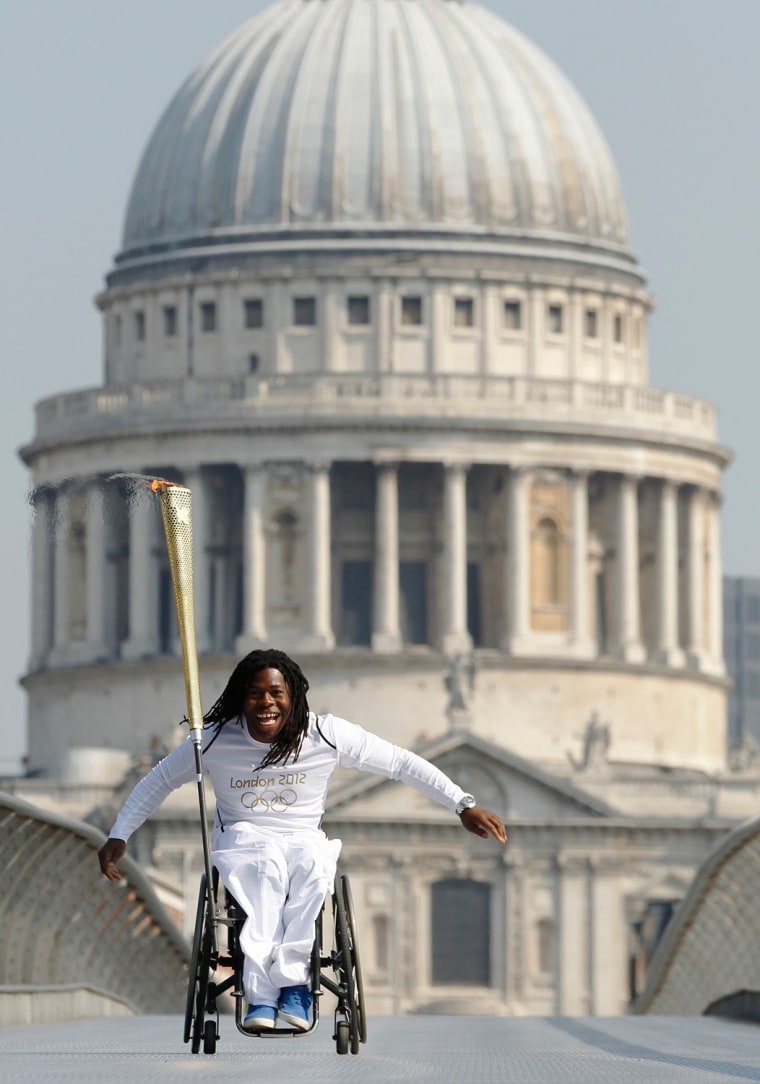 Image: Paralympian Ade Adepitan carries the Olympic Flame across the Millennium Bridge in front of St Paul's Cathedral ahead of the London 2012 Olympic Games