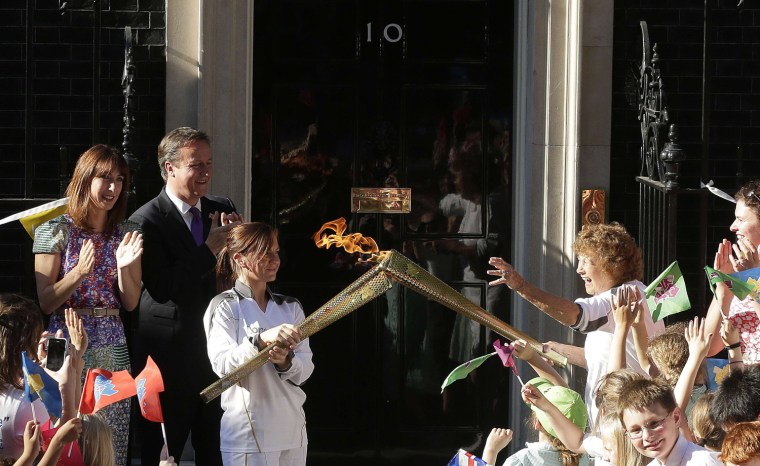 Image: Britain's PM David Cameron and his wife Samantha look on as Olympic torch bearer Florence Rowe receives flame in London