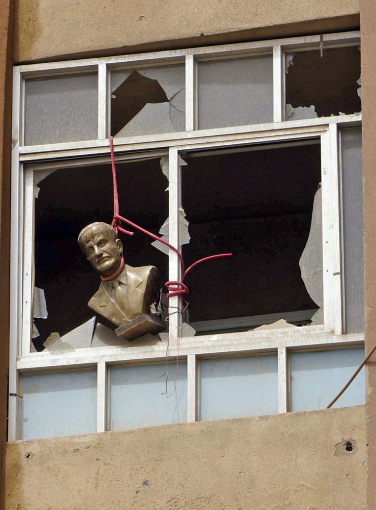 Image: Bust of late Syrian President Hafez al-Assad is seen hung at a broken window of a building in Deir al-Zor
