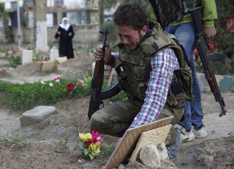 Image: A Free Syrian Army fighter mourns at the grave of his father in a public park that has been converted into a makeshift graveyard in Deir el-Zor