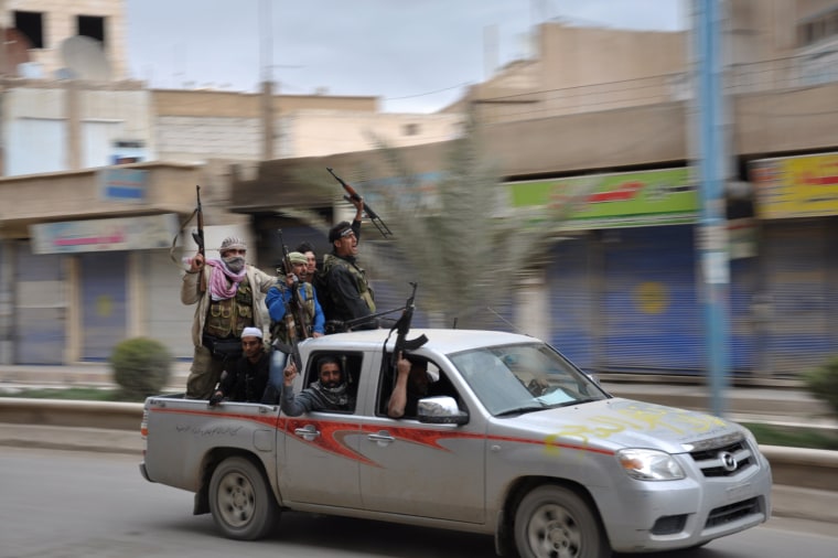 Image: Free Syrian Army fighters carry their weapons and cheer as they drive in the northeastern provincial capital of Raqqa after capturing it