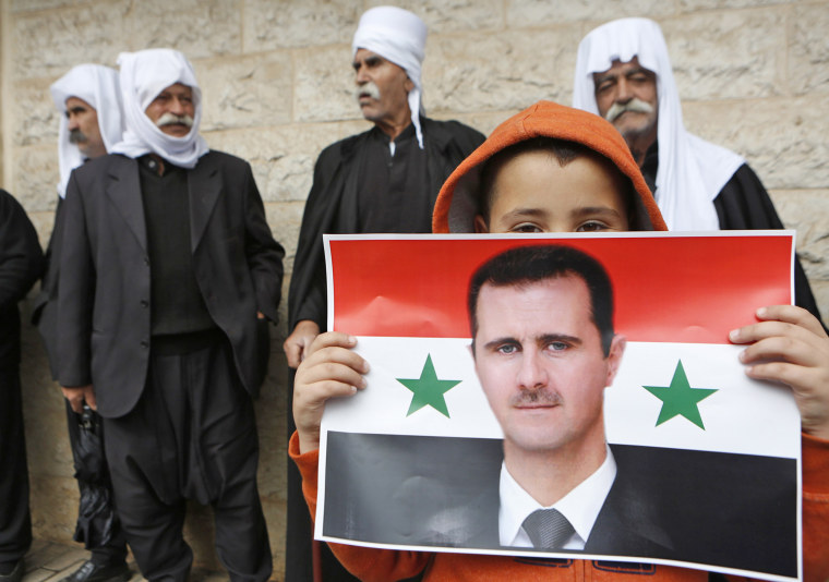 Image: A boy holds a flag with the image of Syria's President Assad during a rally in a Druze village on the Golan Heights