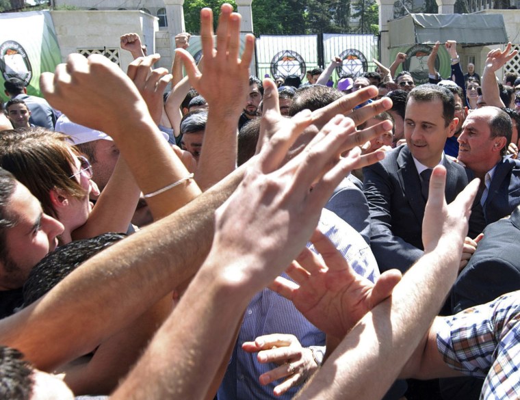 Image: Syria's President Bashar al-Assad walks among his supporters during the inauguration of a memorial, dedicated to university students who died during the ongoing civil war, in Damascus