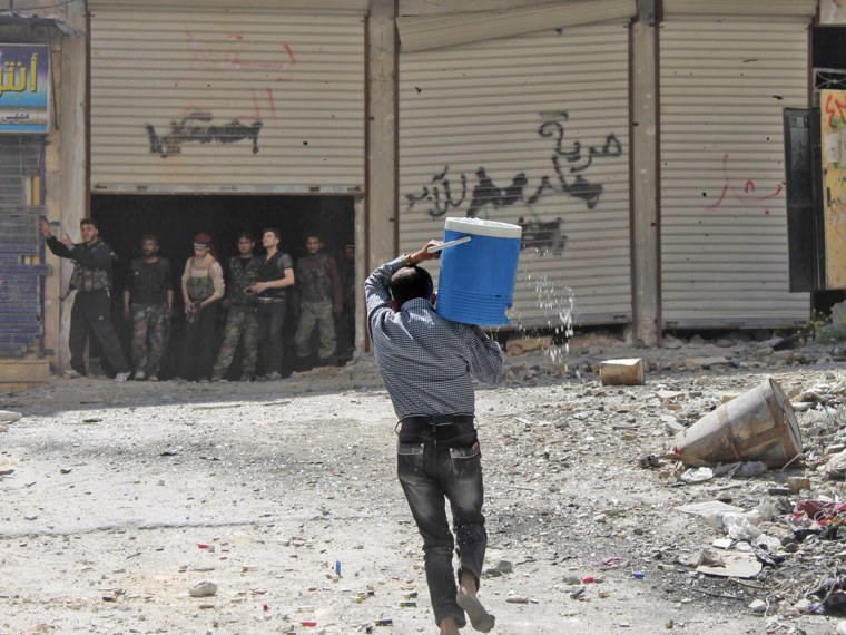 Image: A man holding a water cooler runs to avoid a sniper in Aleppo's Salaheddine neighbourhood