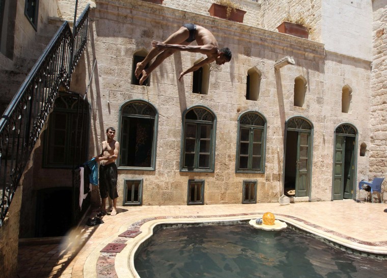 Image: A Free Syrian Army fighter dives into a swimming pool inside a house in the old city of Aleppo