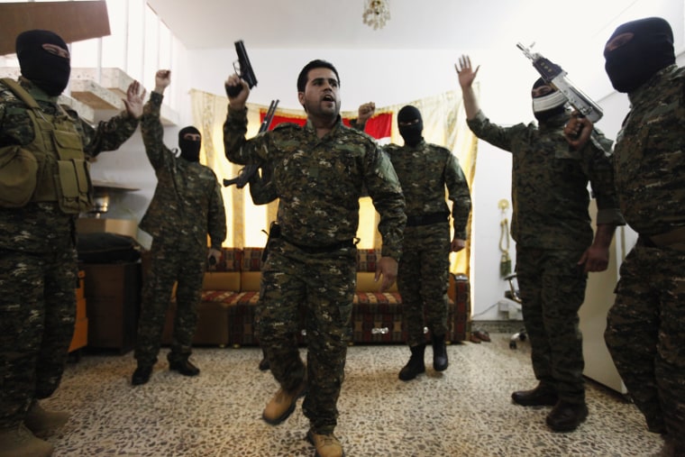 Image: Fighters from Iraq's Shi'ite militias celebrate before departing to Syria from Baghdad