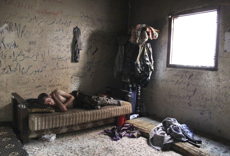 Image: A Free Syrian Army fighter rests inside a house in Aleppo's Karm al-Jabal district