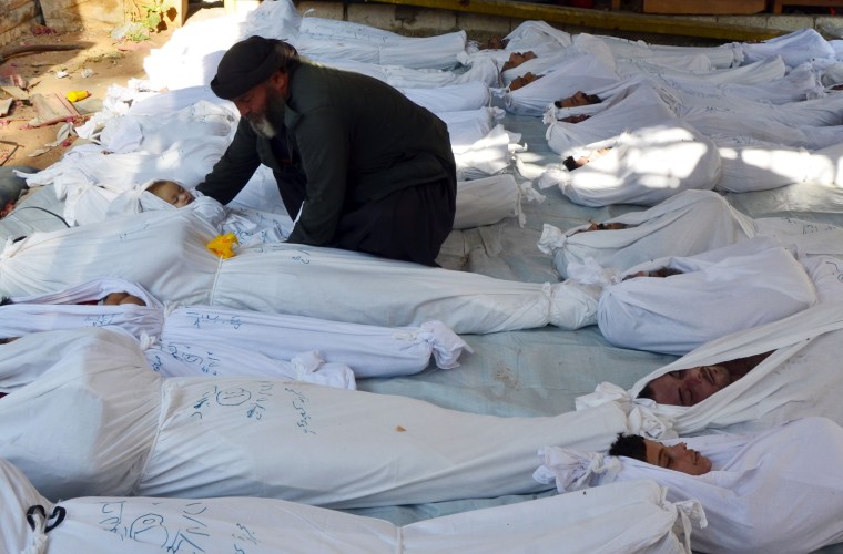 Image: A man holds the body of a dead child among bodies of people activists say were killed by nerve gas in the Ghouta region, in the Duma neighbourhood of Damascus