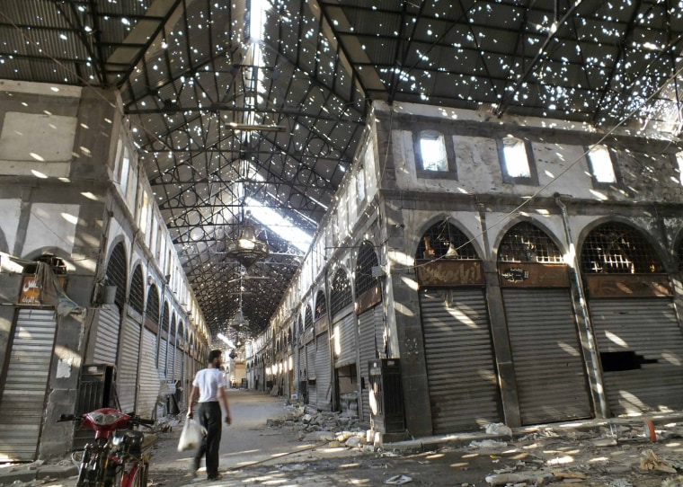 Image: Man walks inside the damaged historical old souk of Homs