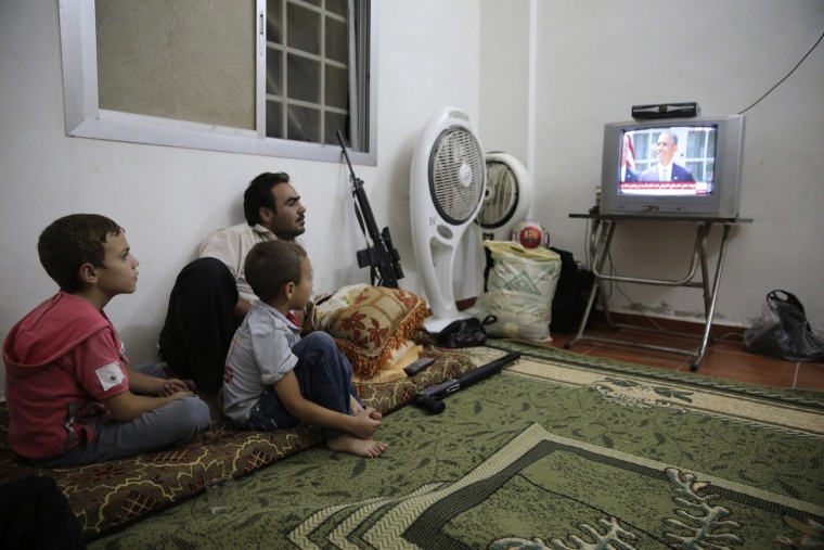 Image: A Free Syrian Army fighter watches U.S. President Barack Obama's speech with his family in Damascus