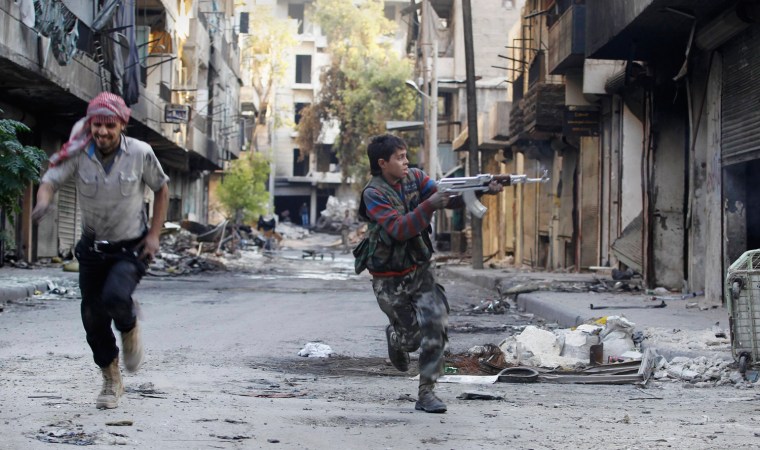 Image: Mohammad, 13 year-old fighter from Free Syrian Army, aims his weapon as he runs from snipers loyal to the Syrian regime in Aleppo's Bustan al-Basha district