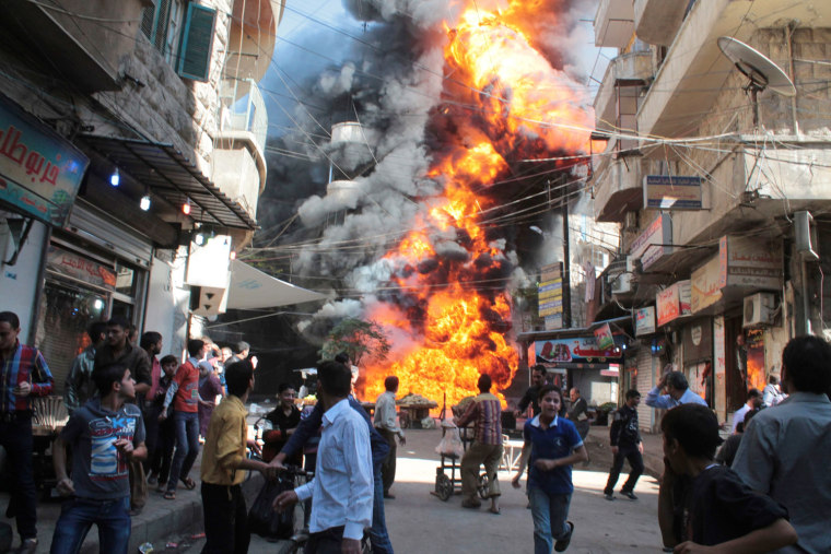 Image: Residents look at a a fire at a gasoline and oil shop in Bustan Al-Qasr