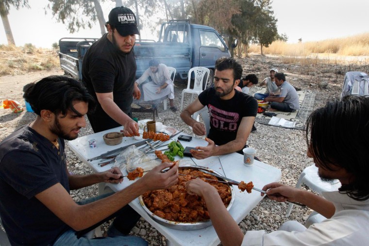 Image: A group of activists from Raqqa eat during an excursion to the Euphrates river in al-Tabaqa