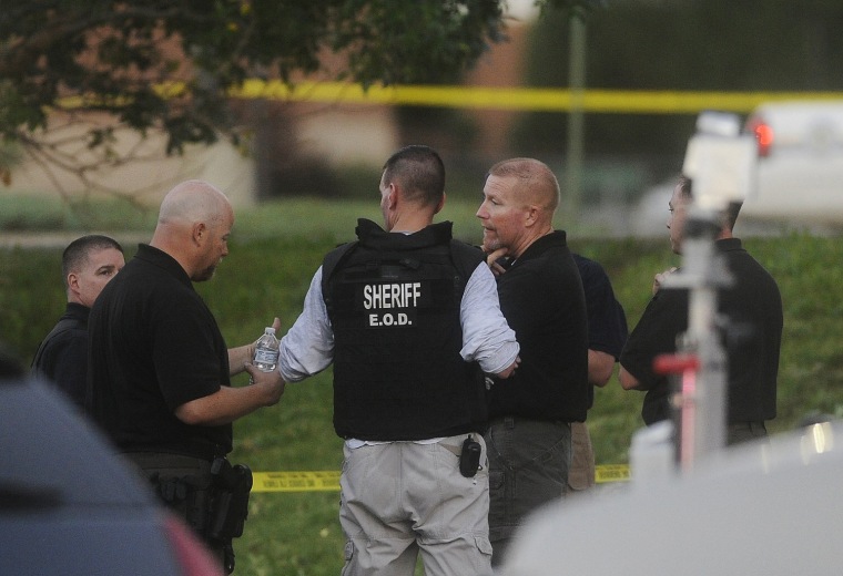 Image: Law enforcement officials gather outside the Century 16 Theatre where a masked gunman killed 14 people in Aurora, Colorado