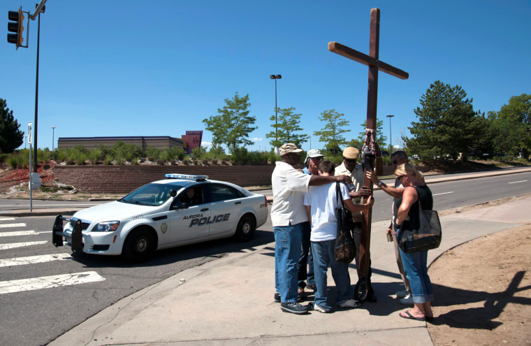 Image: People hold a prayer vigil for the victims and first responders as police investigate an overnight shooting that killed 12 people in Aurora Colorado