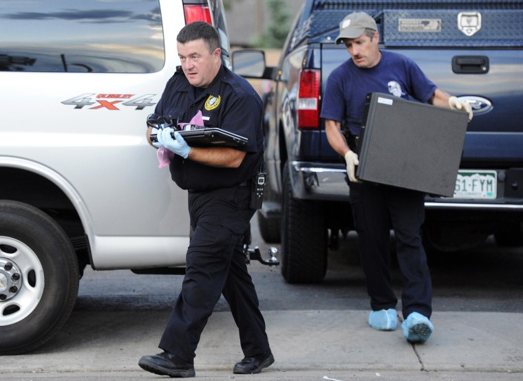 Image: Investigators carry out a laptop, a hard drive, and other evidence from the apartment of the suspect who opened fire in a movie theater in Aurora