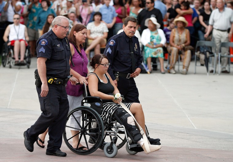 Image: One of the shooting victims is wheeled out of the prayer vigil